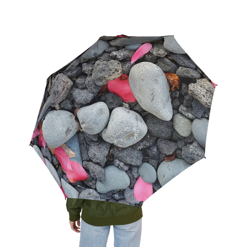 Playa de guijarros con sombrilla de pétalos rosados