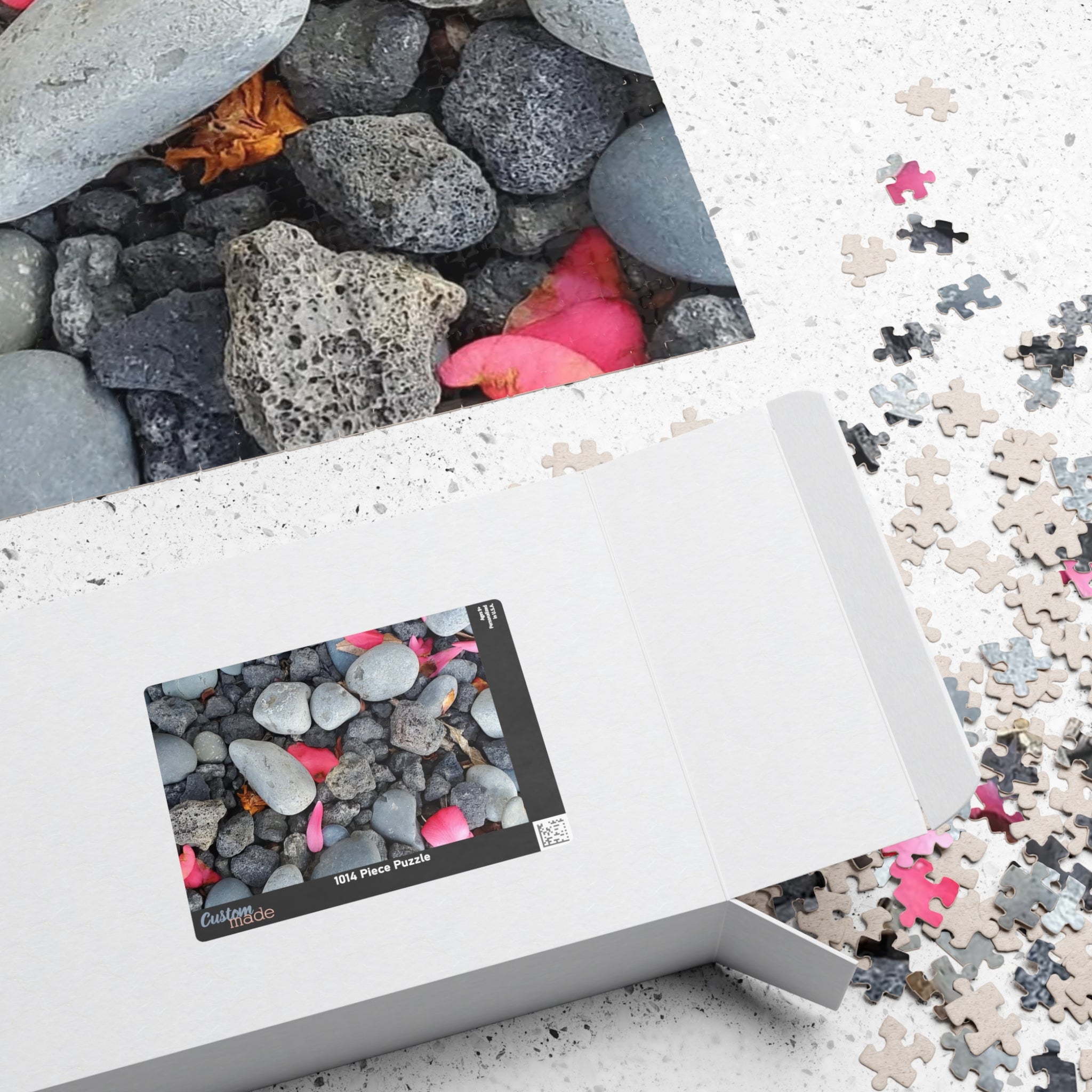 Rompecabezas de pétalos rosas sobre rocas de río