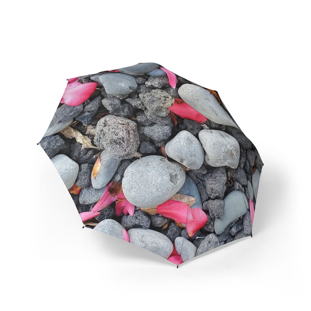 Playa de guijarros con sombrilla de pétalos rosados